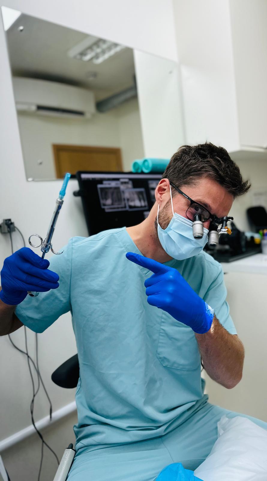 Implant dentist using surgical loupes during a dental implant procedure at SW11 Clinic