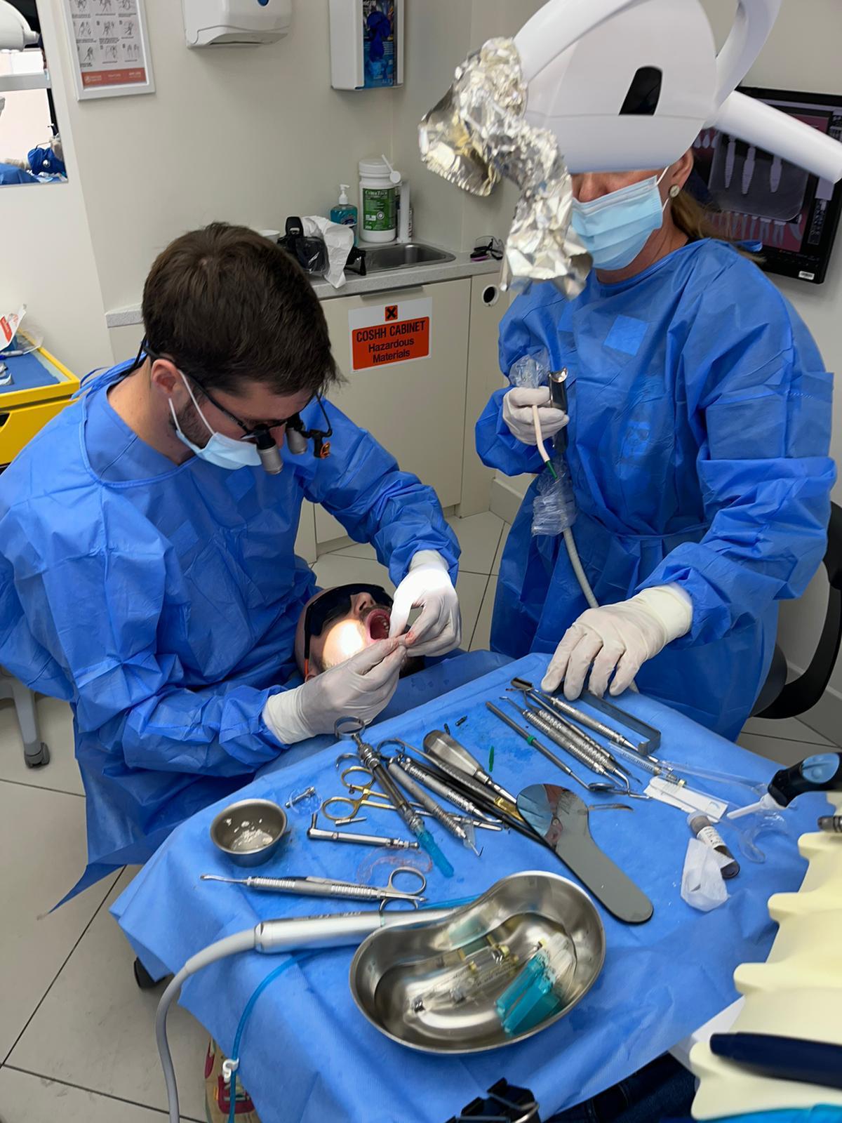 Dr Skorski performing dental implant surgery at SW11 Clinic - two surgeons in surgical gowns